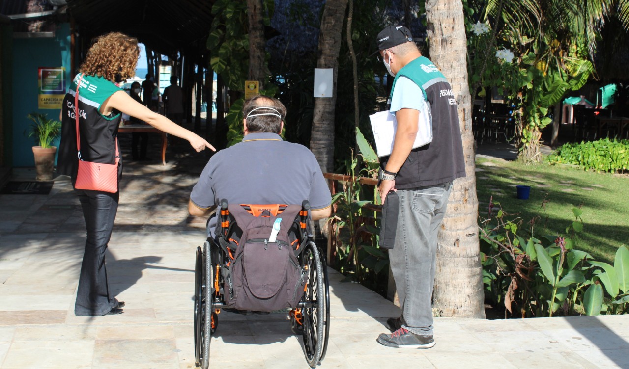 agentes da agefis conversam com uma pessoa de cadeira de rodas